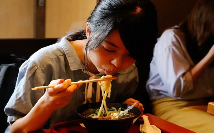 Девушка ест лапшу палочками. / Фото: blog.rosettastone.com